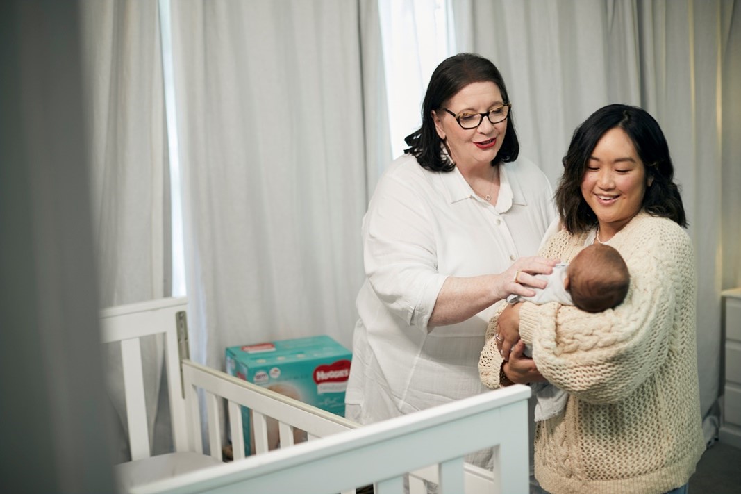 Mum holding wrapped newborn baby with Midwife Cath